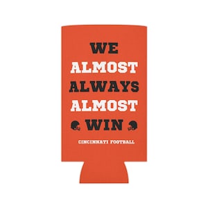 May include: Orange can cooler with black text that reads "WE ALMOST ALWAYS ALMOST WIN" with two black football helmets on either side of the word "WIN". The text "CINCINNATI FOOTBALL" is below the helmets.