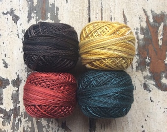 May include: Four balls of embroidery floss in different colors: dark brown, red, yellow, and teal.