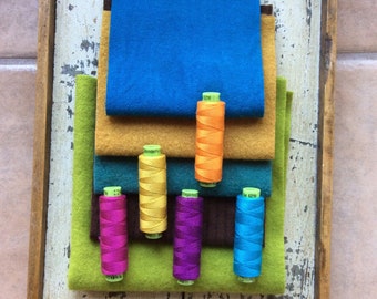 May include: Assortment of colorful felt fabric squares with spools of thread in various colors, including yellow, orange, blue, and purple.