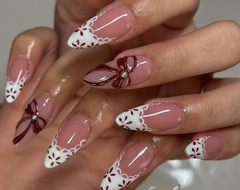 シンプルで上品な白いフレンチチップに赤いリボンのコケット。プレス