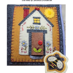 May include: A handmade felt needle minder with a house design. The house is white with a brown door, red chimney, and yellow window. Includes a bee-shaped pincushion. Finished size is approximately 6 inches x 6 inches.