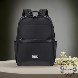 May include: Black backpack with multiple compartments and a top handle. Features a front pocket with a zipper and a small rectangular label that reads "Shouldcat". The backpack has padded shoulder straps and a sleek, modern design.