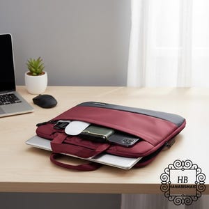 Könnte beinhalten: Eine weinrote Laptoptasche mit grauem Oberteil, geöffnet, um einen Laptop, ein Telefon, eine Maus und anderes Zubehör zu zeigen. Die Tasche hat einen Griff und einen Reißverschluss. Das Logo "HB HANABISMAID" befindet sich unten rechts.