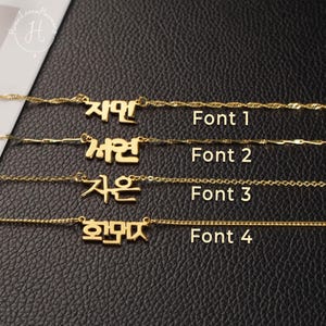 May include: Four gold-coloured necklaces with nameplates featuring Korean characters. Each necklace displays a different font style labelled Font 1, Font 2, Font 3, and Font 4. The chains have distinct link patterns, and the nameplates are centred on each chain.