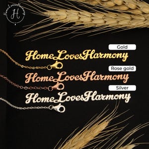 May include: Three nameplate necklaces in gold, rose gold, and silver finishes. Each necklace features the text HomeLovesHarmony in a cursive script font, attached to a delicate chain with a lobster claw clasp. Labels indicate the metal colors.