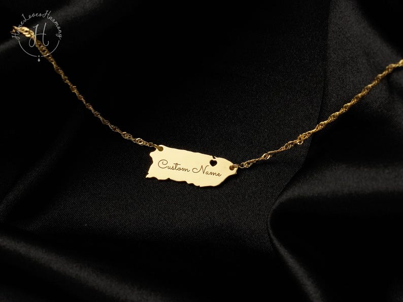 May include: A gold-toned necklace featuring a pendant shaped like the island of Puerto Rico. The pendant includes a small heart cutout and the engraved text "Custom Name" in a cursive script. The pendant is attached to a delicate twisted chain.