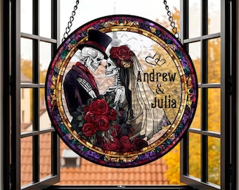 May include: Round stained glass window art featuring a skeleton couple in formal attire, embracing. The bride wears a veil and a floral headpiece, holding a bouquet of red roses. The groom wears a top hat. The names "Andrew & Julia" are displayed.