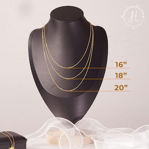 May include: Three gold-toned chain necklaces displayed on a black mannequin bust. The chains are layered at lengths of 16 inches, 18 inches, and 20 inches, as indicated by horizontal lines and text labels next to each individual necklace strand.