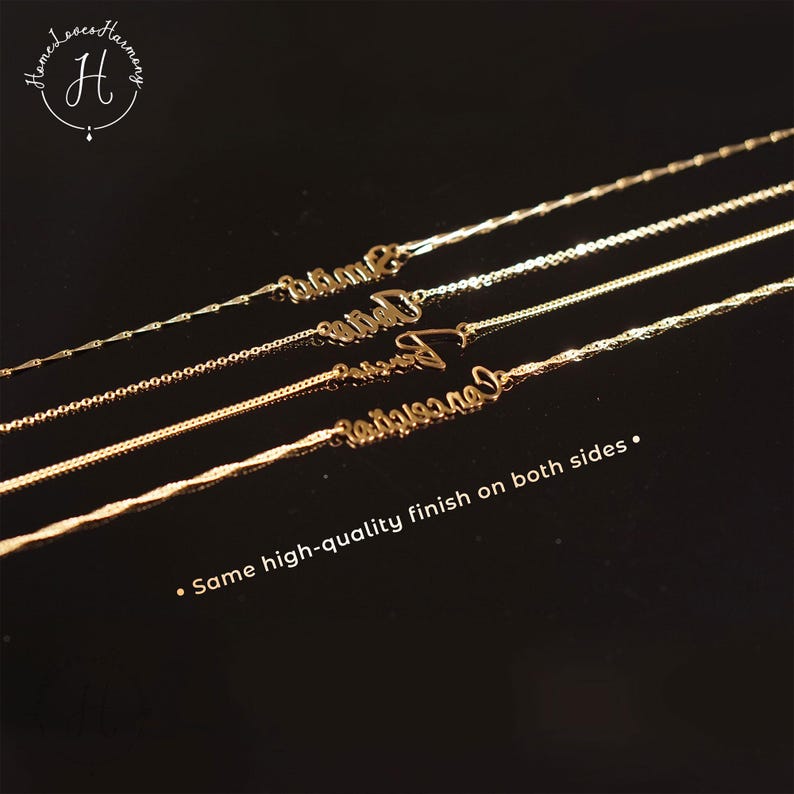 May include: Four gold-toned necklaces with cursive name pendants arranged diagonally. Each necklace features a distinct chain style. The text "HomeLovesHarmony" with an H logo is in the top left, and "Same high-quality finish on both sides" is at the bottom.
