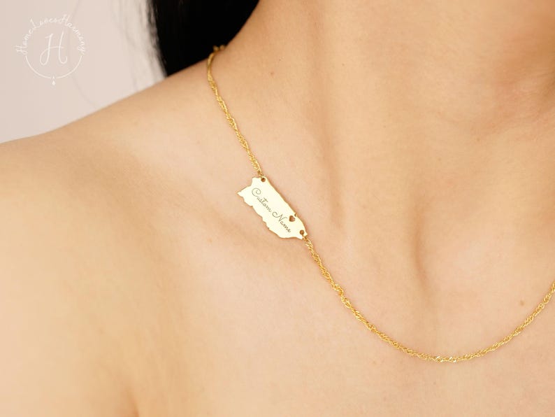 May include: A gold-toned necklace featuring a delicate twisted chain and a small, asymmetrical pendant plate. The pendant is engraved with the text 'Custom Name' in a cursive script, accompanied by a tiny heart symbol near the right edge.