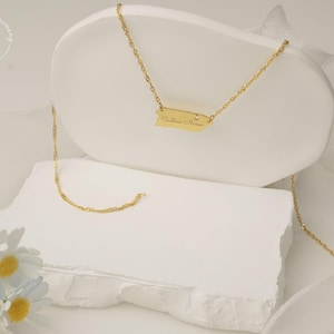 May include: A gold-toned necklace featuring a pendant shaped like the island of Puerto Rico. The pendant is suspended from a delicate twisted chain and includes the engraved text Custom Name on its surface, showcasing a polished metallic finish.