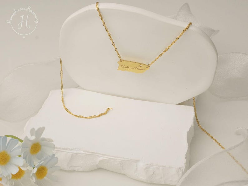 May include: A gold-toned necklace featuring a pendant shaped like the island of Puerto Rico. The pendant is suspended from a delicate twisted chain and includes the engraved text Custom Name on its surface, showcasing a polished metallic finish.