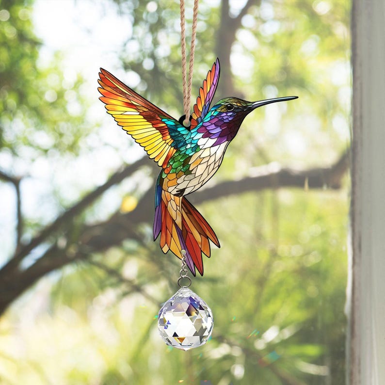 May include: A stained glass hummingbird with iridescent colors, hanging from a window with a crystal prism hanging below.