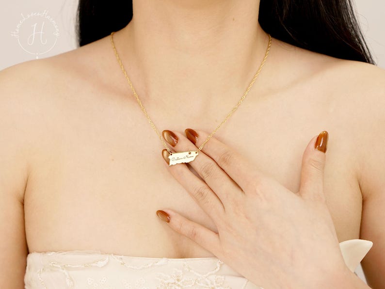 May include: A gold-toned necklace featuring a small, horizontal pendant shaped like the island of Puerto Rico. The pendant is engraved with the cursive text "Culebra & Vieques" and is suspended from a delicate, thin gold-toned chain.