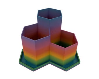 May include: A desk organiser with multiple compartments, featuring a rainbow gradient. The hexagonal organiser is painted with a blend of colours, including blue, purple, orange, yellow, and green. It sits on a matching base.