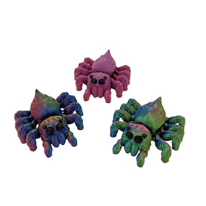 May include: Three colorful spider figurines. One is purple, another is a mix of blue and green, and the third is a mix of blue, green, and purple. Each has multiple legs and two large eyes.