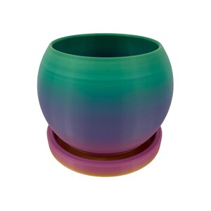 May include: A spherical planter with a matching saucer. The planter transitions from green at the top to blue-green, then purple at the bottom. The saucer is a gradient of pink and yellow. The planter is suitable for small plants.
