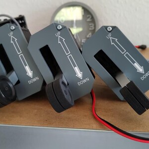 May include: A set of black and gray mechanical controls with red and black wires. Three gray panels have white arrows and the words "UP" and "DOWN". A black dial reads "PEDAL DISC".
