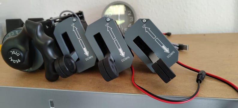 May include: A set of black and gray mechanical controls with red and black wires. Three gray panels have white arrows and the words "UP" and "DOWN". A black dial reads "PEDAL DISC".