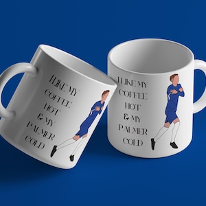 May include: Two white ceramic mugs with black text and a blue cartoon figure. The text on the mugs reads "I like my coffee hot & my Palmer cold".