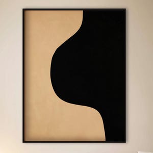 May include: Abstract art print with a black and beige colour block design. The artwork is framed in a black frame and hangs on a neutral-coloured wall. The room also includes a white sofa, black side tables, and a round coffee table.