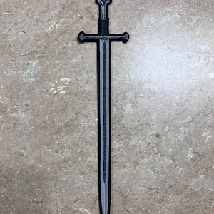 May include: A black sword with a crossguard and a pointed tip. The sword has a textured appearance and is set against a neutral background. The sword's handle has a decorative design.