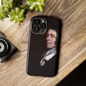 May include: A black phone case with a portrait of a man in a white collar and dark clothing. The case has a camera lens cutout with three lenses.