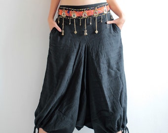 May include: A woman wearing a maroon crop top, a black and orange patterned belt with gold accents, and black harem pants with a gathered detail at the ankles. She is wearing black heeled sandals.
