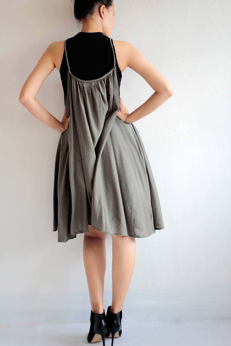 May include: A grey sleeveless dress with a loose, flowing fit. The dress has a scoop neck and a slightly gathered skirt.
