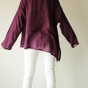May include: A long-sleeved, loose-fitting, purple shirt with a slightly asymmetrical hemline. The shirt is made of a soft, lightweight fabric and has a relaxed fit.