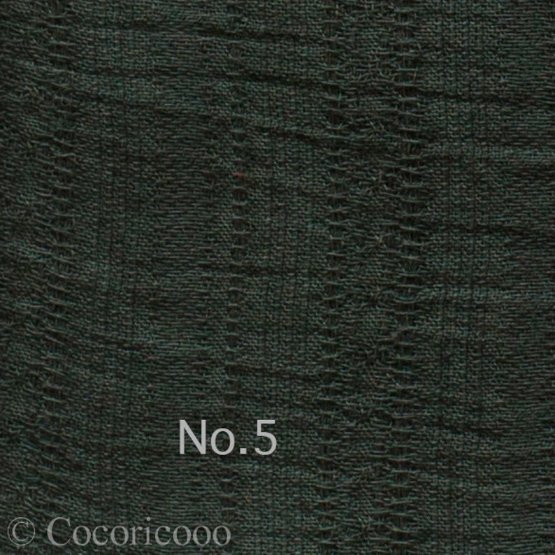May include: A close-up of a dark green fabric with a textured woven pattern. The fabric has a subtle sheen and a slightly rough texture. The text "No. 5" is printed in white on the fabric.