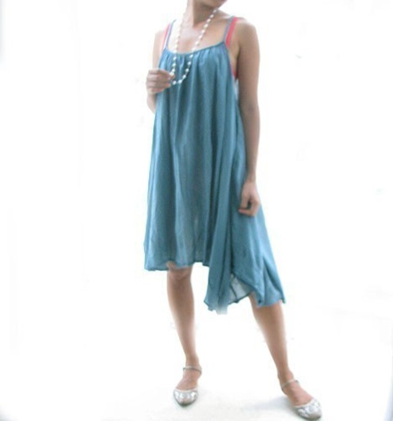 May include: A light blue sleeveless dress with a slightly asymmetrical hemline. The dress is made of a soft, flowing fabric and has a relaxed fit.
