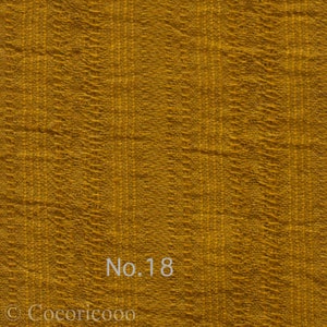 May include: A close-up of a textured, mustard yellow fabric with the text "No. 18" printed on it.