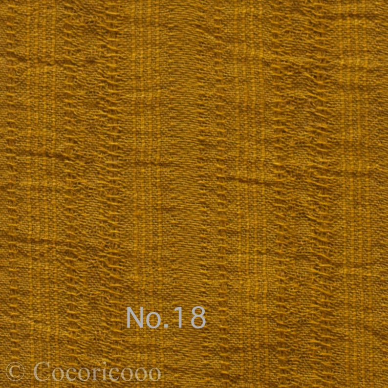 May include: A close-up of a textured, mustard yellow fabric with the text "No. 18" printed on it.