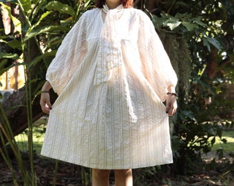 Vestido estilo babydoll em algodão: decote em V com pregas costuradas à mão, modelagem ampla.