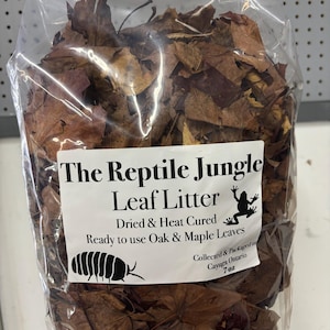 May include: A transparent bag containing dried oak and maple leaves, labelled "The Reptile Jungle Leaf Litter". The label features a frog and pill bug illustration. The bag contains 198 grams of leaf litter.
