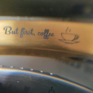 May include: Gold-colored metal band with the engraved text "But first, coffee" and a small coffee cup icon.