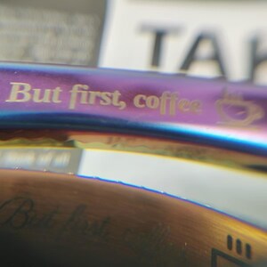 May include: A stainless steel reusable straw with a rainbow iridescent finish. The straw has the text "But first, coffee" engraved on it.