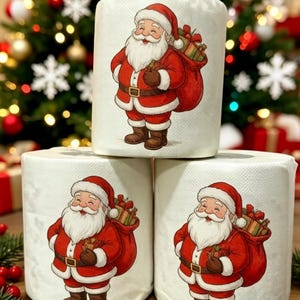 Può includere: Tre rotoli di carta igienica bianca, ognuno con un'illustrazione stampata di Babbo Natale che indossa un abito rosso e porta un sacco di regali sulla schiena. La figura ha una barba bianca, stivali marroni e un'espressione sorridente.