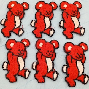 May include: Set of ten red felt embroidered teddy bear patches. Each patch features a teddy bear with a white belly and a red outline.