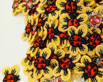 May include: A collection of yellow fabric ladybug appliques with black wings and red spots. The appliques are perfect for adding a touch of whimsy to crafts and projects.