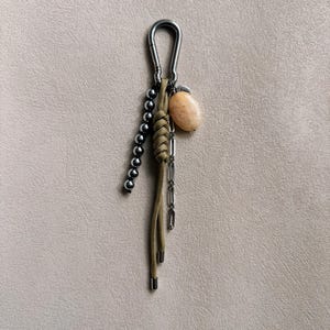 May include: A set of three ceramic mugs with a speckled, matte finish. The mugs are in shades of cream, light gray, and dark gray. Each mug has a simple, minimalist design and a rounded handle. The mugs are stacked on top of each other.