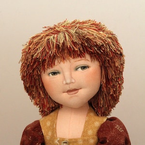 May include: A handmade doll with red yarn hair, wearing a brown and gold dress with a white lace trim and buttons.