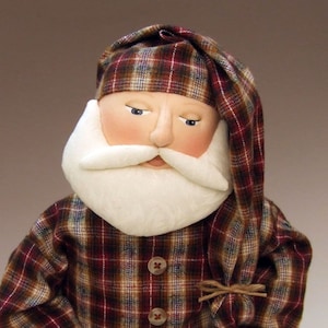 May include: A handmade Santa Claus doll wearing a red and brown plaid flannel shirt and matching hat. The doll has a white beard and a painted face.
