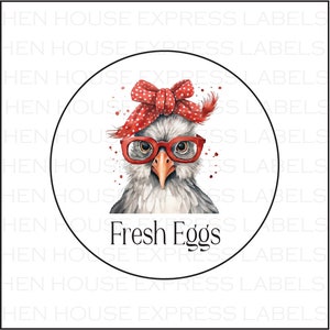 May include: A white circle with a black outline containing a cartoon illustration of a chicken wearing red-rimmed glasses and a red and white polka dot bow. The chicken is looking directly at the viewer. The text 