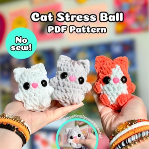 May include: Three crocheted cat stress balls in white, gray, and orange-white, each with black safety eyes and a pink nose. The text reads Cat Stress Ball PDF Pattern and No sew!. A circular inset shows a hand squeezing the gray cat stress ball.