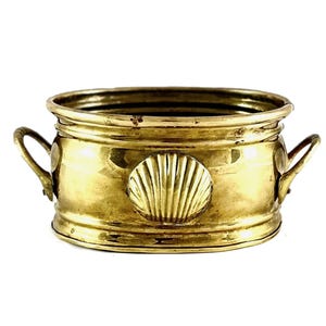 May include: A brass planter with a seashell design. The planter has a round shape with two handles and a decorative seashell in the center. The brass has a shiny, golden colour.