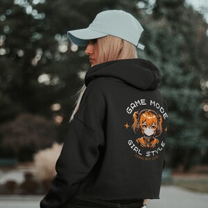 May include: Black cropped hoodie with a graphic of an anime girl wearing headphones and the text "Game Mode Girl Style Feral But Cute".