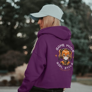 May include: Purple cropped hoodie with a graphic of a girl in a headset with the text "Game Mode Girl Style Feral But Cute" on the back.
