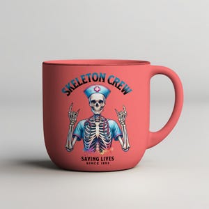 May include: A pink ceramic mug with a skeleton wearing a nurse's uniform and a stethoscope. The mug has the text "Skeleton Crew Saving Lives Since 1853".